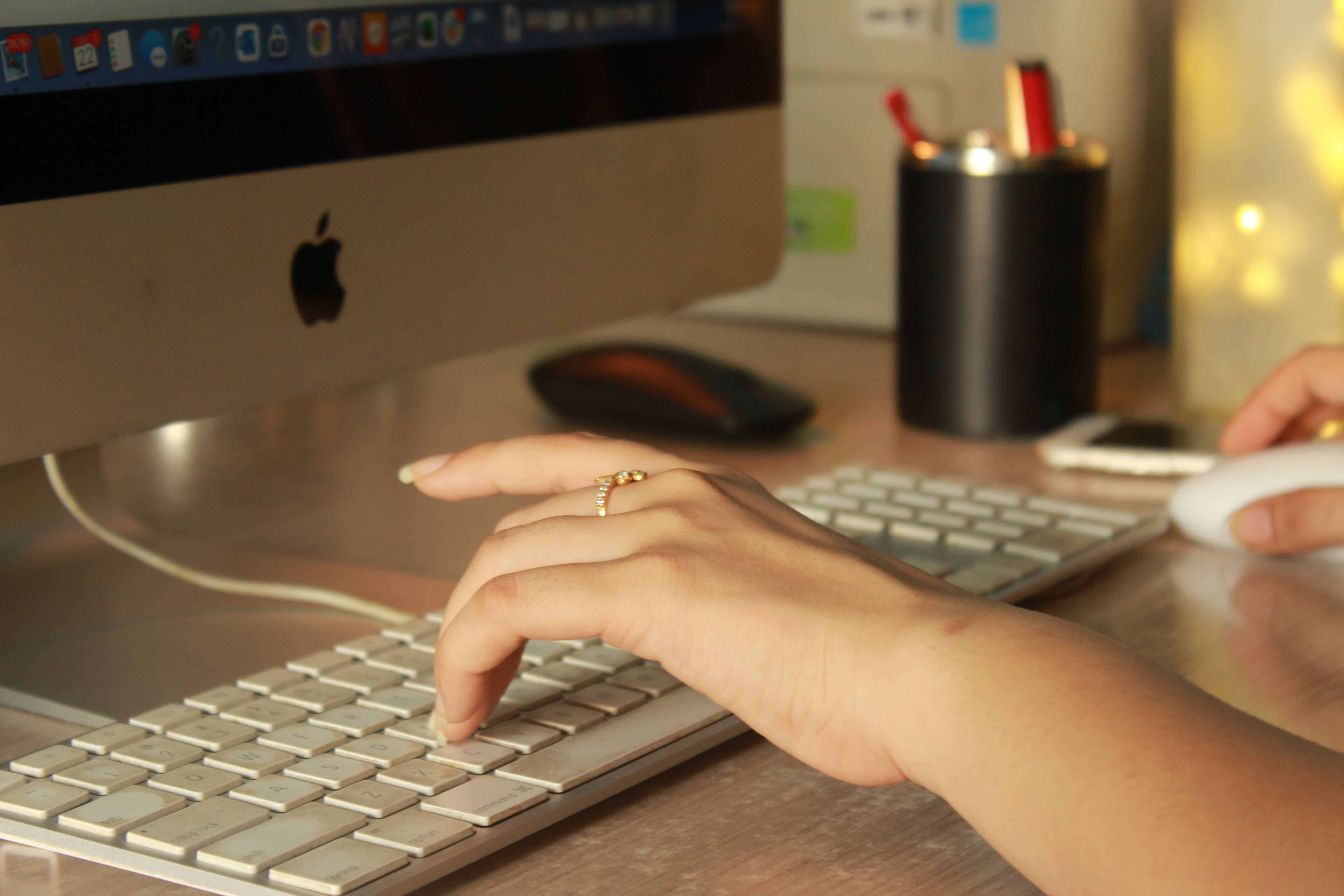Close-up of a hand typing on a keyboard, describing a task in plain language